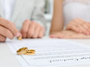 Mesa de trabajo con manos firmando pactos matrimoniales y documentos legales.